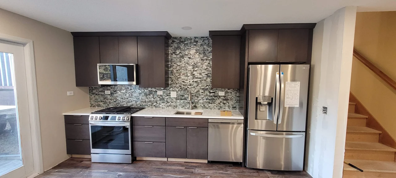 Kitchen with dark cabinets, patterned backsplash, stainless appliances, and a central island